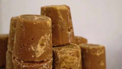 Pure organic jaggery blocks stacked up against white background Stock Footage