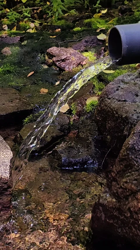 Pure spring water flowing from pipe into stream. Stock Footage 334785129