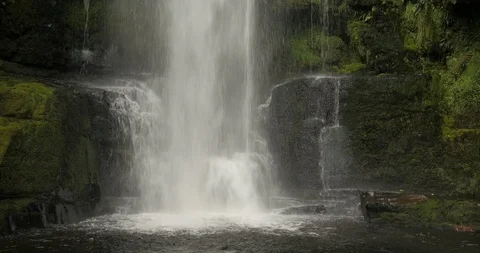 Pure white waterfall cascades down mossy covered rocks into a pool Stock Footage 120431941