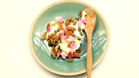 Pure yogurt topped with walnuts, almonds, raisins, and pumpkin seeds Stock Footage 335632244
