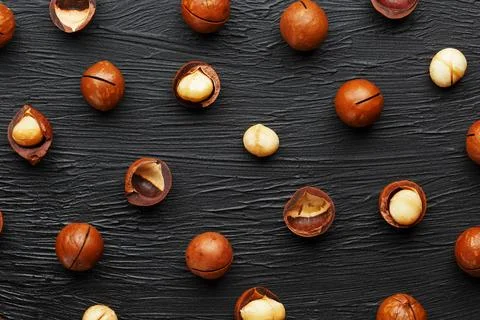 Purified and shell repeats macadamia nuts on black textural stone backgroun.. Фото