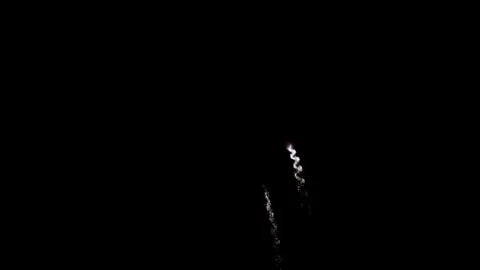 Purple and white fireworks explode in the dark sky Stock Footage 329675748