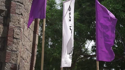 Purple and White Flags Waving by Stone Church Wall in San Rafael, Bulacan Stock Footage 319925009