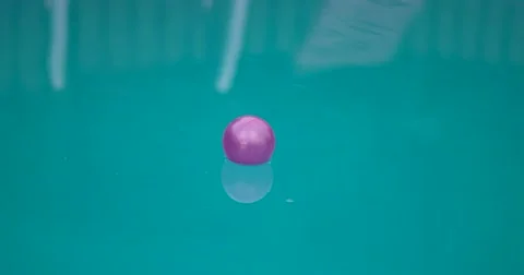 Purple Ball Floating on Water Surface of a Swimming Pool Stock Footage 64767260
