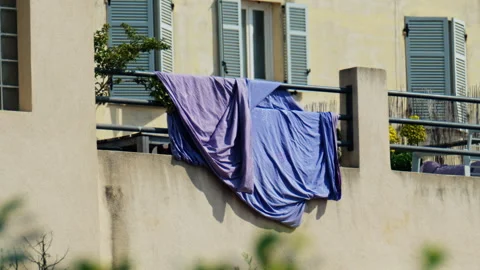 Purple bed sheets drying on a balcony on a sunny day Stock Footage 305865254