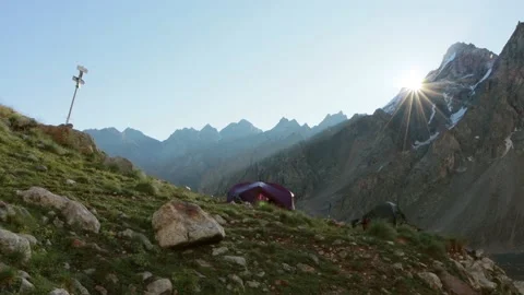 A purple camping tent among the sharp rocky mountains in the morning. A Scenic Stock Footage 169706859