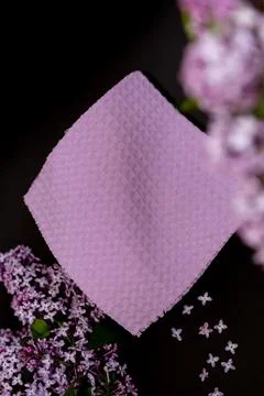 Purple cloth on dark surface surrounded by lilac flowers and scattered peta.. Stock Photos