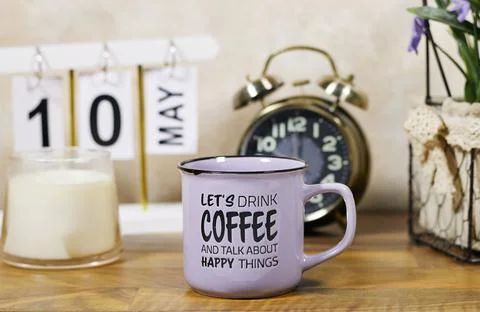 Purple coffee mug reading 'Let's drink coffee and talk about happy things' sits  Stock Photos