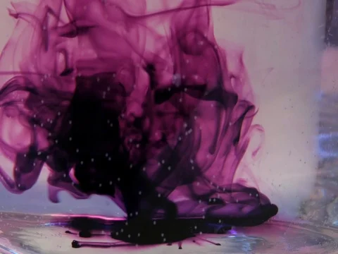 Purple crystals of potassium permanganate dissolve in the whirlpool of water Stock Footage