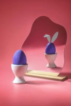 Purple Easter egg on a stand, opposite, an egg with bunny ears is reflected i Stock Photos