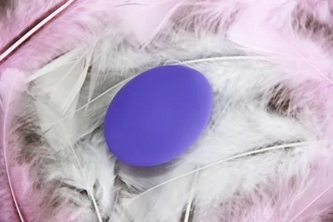 Purple easter egg very peri on colorful feathers Stock Photos