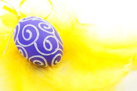 Purple easter egg on yellow feathers Stock Photos
