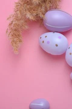 Purple Easter eggs next to dry grass. Pink background. Easter. Stock Photos