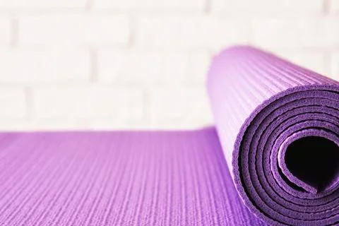 Purple exercise mat close to the brick wall in the fitness room Stock Photos