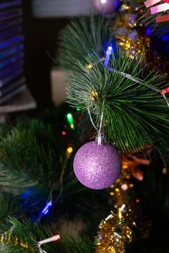 Purple glitter bauble with multicolored string lights bokeh Stock Photos