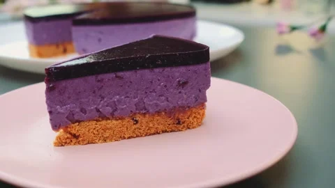 Purple layered cheesecake slice resting on pink plate indoors Vidéo 342883729