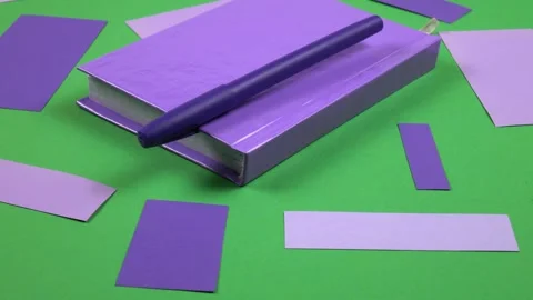 Purple notepad, sticky notes and ballpoint pen lie on a green background Stock Footage 336507367