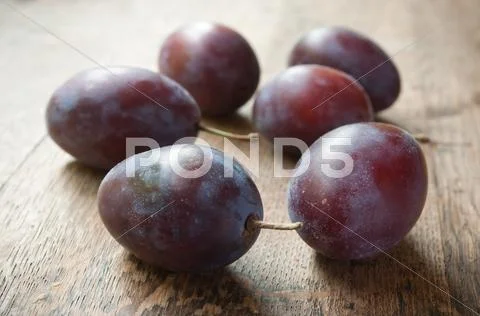 Purple plums on wooden table background Stock Photos
