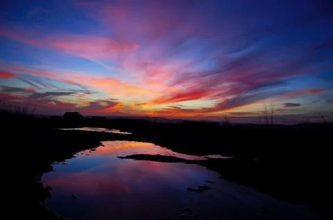 Purple-red sunset reflected in a puddle of water Stock Photos