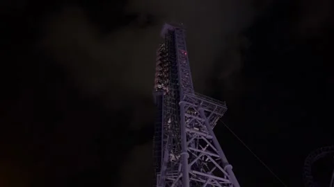 Purple roller coaster with a train on tracks at dark night Stock Footage 336179933