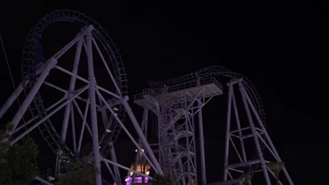 Purple roller coaster with a train on tracks at dark night Stock Footage 336180101