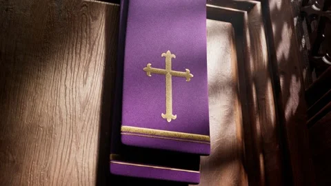 Purple stole with cross lightened by rays of light falling into a confessional. Video stock 145767873