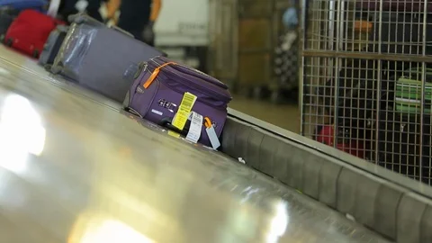 Purple suitcase arriving in baggage claim at airport Stock Footage 123729765
