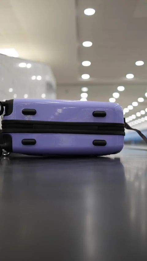 Purple suitcase on conveyor 库存影片 327925321