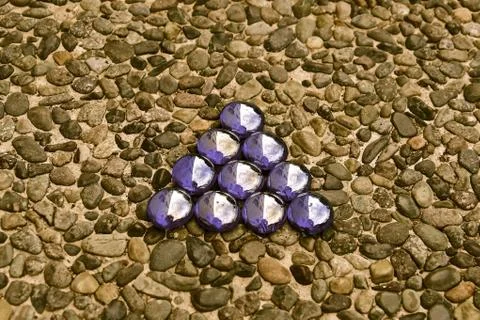 Purple triangle on pebblestone background Stock Photos