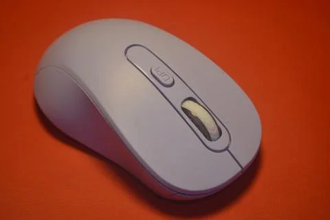 A purple wireless computer mouse isolated on red background Stock Photos