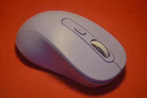 A purple wireless computer mouse isolated on red background Stock Photos