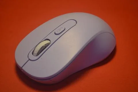 A purple wireless computer mouse isolated on red background Stock Photos