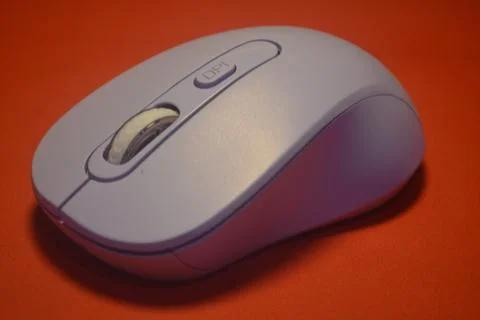 A purple wireless computer mouse isolated on red background Stock Photos