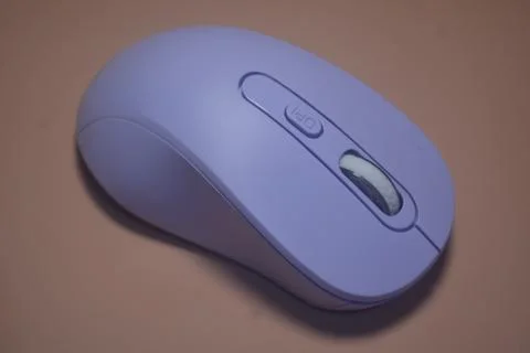 A purple wireless computer mouse isolated on pink background Fotos de archivo