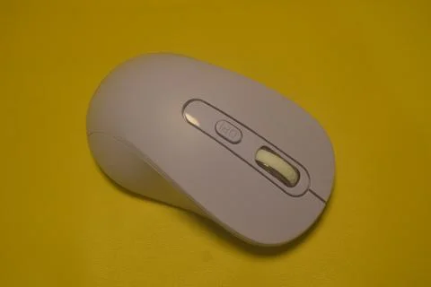A purple wireless computer mouse isolated on yellow background Fotos de archivo