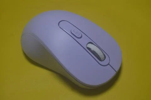 A purple wireless computer mouse isolated on yellow background Stock Photos