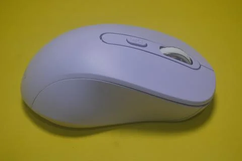 A purple wireless computer mouse isolated on yellow background Stock Photos