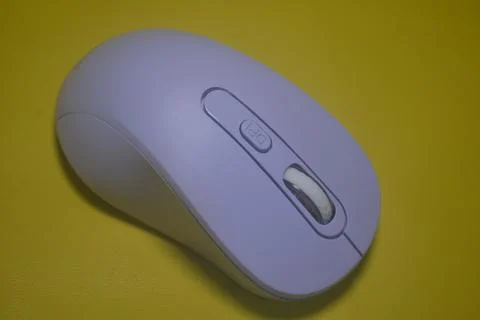 A purple wireless computer mouse isolated on yellow background Stock Photos