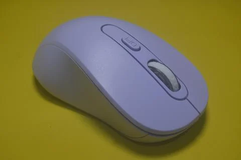 A purple wireless computer mouse isolated on yellow background Stock Photos