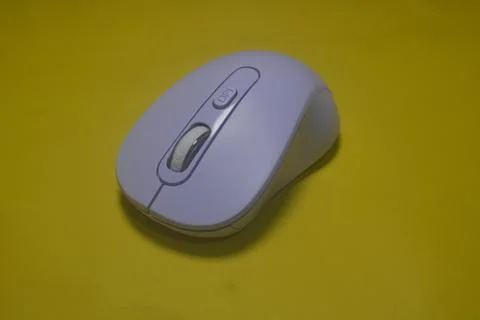 A purple wireless computer mouse isolated on yellow background Fotos de archivo