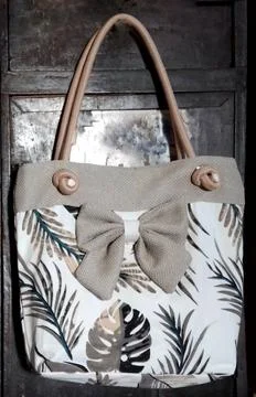 	A purse with a leaf pattern and a bow on it. Stock Photos