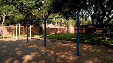 Push into and dolly left footage of empty swings of a playground Stock Footage 115954464