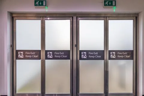 Push bar exit doors with emergency signage in public building interior Fotos de archivo