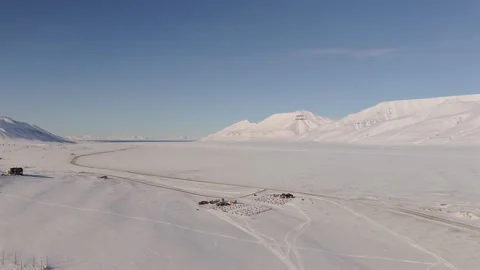 Push Forward Aerial Over Snowy Valley Toward Dog Sledding Station in Svalbard Stock Footage 345950024