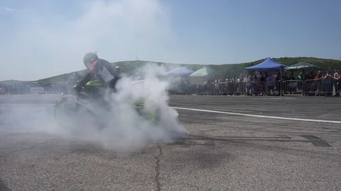 Push in on motorcycle racer burning back tire before start of drag race. Stock Footage 115802945