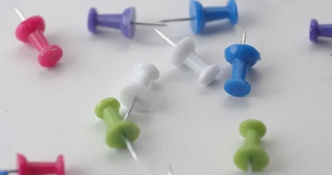 Push pins dropped onto white surface in slow motion Stock Footage 117350008