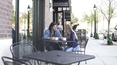 Push-in shot of a couple sitting in front of a coffee shop Stock-Footage 76538969