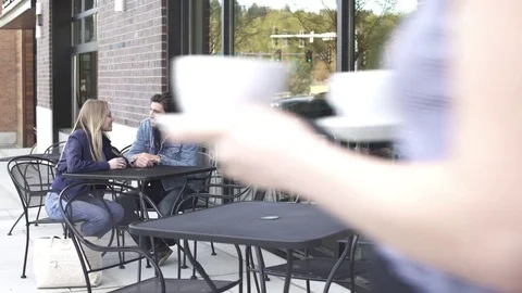 Push-in shot of a couple sitting in front of a coffee shop Stock Footage 76538981