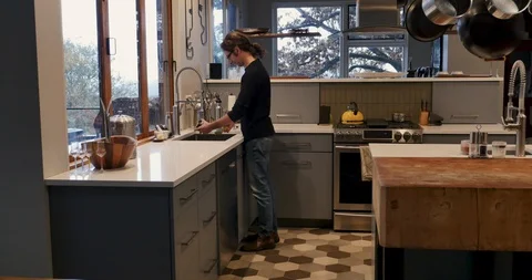 Push in shot of a man cleaning coffee cups alone in a modern kitchen Stock Footage 128176681