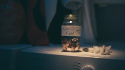 Push-in shot of a tip jar filled with coins on top of a washing machine, USA Stock Footage 236101817